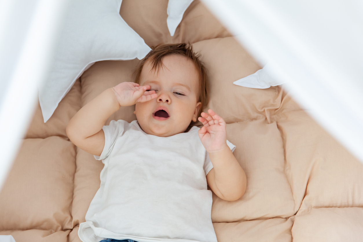 Newborn baby yawning, signaling it is time for sleep.