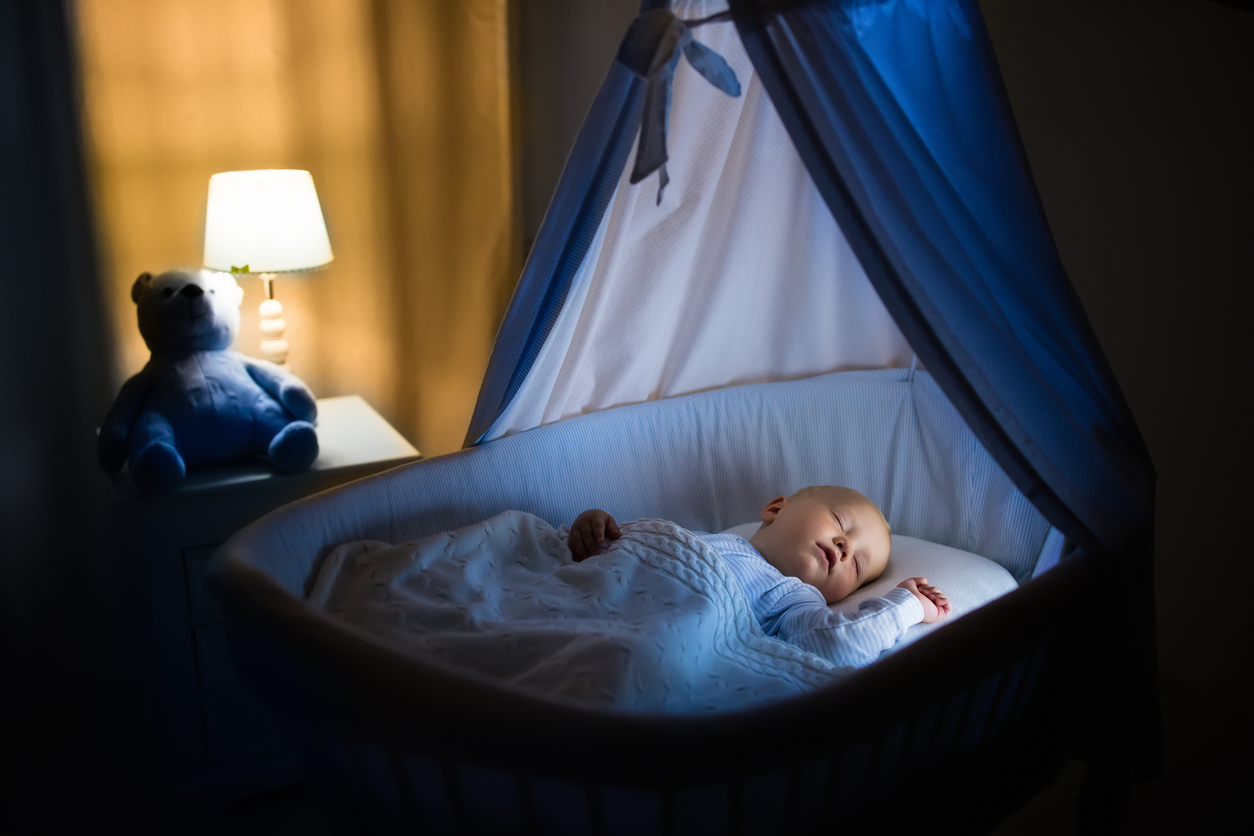 A softly lit nursery with a teddy bear on the nightstand.